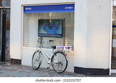 TOKYO, JAPAN - May 3, 2022: A Mizuho Bank ATM facility with a police bicycle outside which warns people about telephone scammers. It's in Tokyo's Koto Ward.