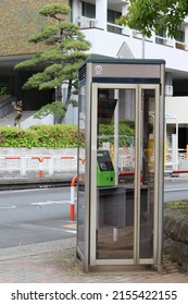 TOKYO, JAPAN - May 8, 2022: Phone box with Tokyo's Koto Ward's city offices in the background.