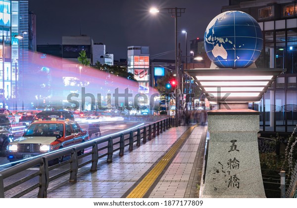 tokyo, japan - november 02 2019: Cars headlights\
lighting up the Olympic Bridge named Gorinbashi created for 1964\
Summer Olympics in Harajuku district and decorated with an earth\
globe at night.