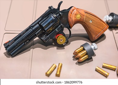 tokyo, japan - november 10 2020: Close-up on a replica of an american revolver Colt python 357 magnum CTG caliber of 4-inch barrel with speed loaders full of cartridges or bullets.