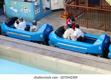 TOKYO, JAPAN - November 11, 2021: Poncho-clad Rider Preparing For The Start Of The Wonder Drop Ride In Tokyo Dome City Attractions Amusement. People Wear Face Masks Due To Coronavirus.