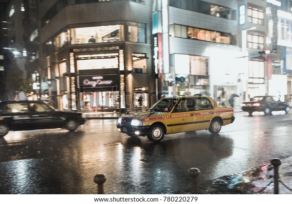 TOKYO, JAPAN - NOVEMBER 13, 2017: Taxi driving in\
the rain through wet\
street.