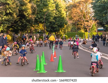 Tokyo, Japan - November 17 2019: Parents Watching Over Children Wearing Helmets Practicing Bicycles On Training Bikes