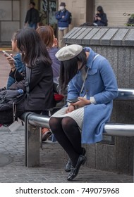 TOKYO, JAPAN - NOVEMBER 4TH, 2017. Young girl with smartphone sitting on a bench in Hachiko square, Shibuya - Shutterstock ID 749075968