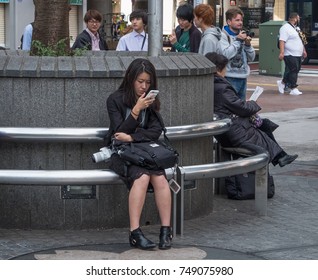 TOKYO, JAPAN - NOVEMBER 4TH, 2017. Young girl with smartphone sitting on a bench in Hachiko square, Shibuya - Shutterstock ID 749075980