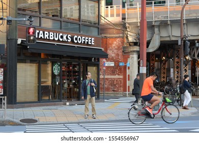 TOKYO, JAPAN - November 9, 2019: A Starbucks Coffee Shop On A Busy Street Corner In Tokyo's Kanda Area. A Train Is Passing On A Bridge In The Background. Some Motion Blur.