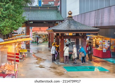 Tokyo, Japan - October 14 2019: Japanese Elderlies In The Rain Purifying Their Soul With Incense Smoke Around A Buddhist Censer Overlooked By A Suientsuki-robanhouju In The Koganji Temple Of Sugamo.