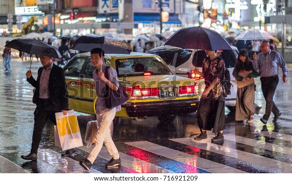TOKYO, JAPAN - SEPTEMBER 16TH, 2017. Taxi trapped in the\
middle of Shibuya famous pedestrian scramble crossing during a\
rainy night. 