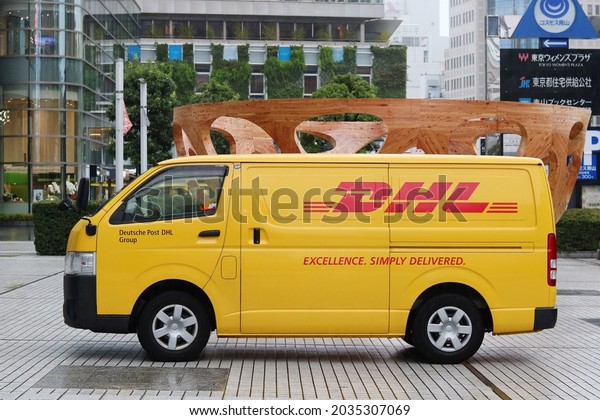 TOKYO, JAPAN - September 2, 2021: DHL delivery\
van at United Nations University by Global Bowl art work on rainy\
day. Sculpture is part of Pavilion Tokyo project of art displayed\
during Tokyo Olympics