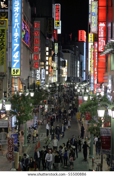 TOKYO - JUNE 13: People walk\
through light up streets with neon signs on June 13, 2010 in\
Tokyo.