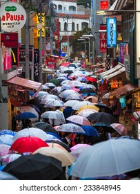 TOKYO - October 5 2014: People Walk Through Takeshita Dori Near Harajuku Train Station With Umbrella In A Raining Day On October 5 2014. Harajuku Is Considered A Birthplace Of Japan's Fashion Trends.