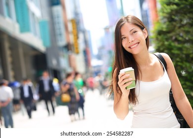 Tokyo Urban Woman Commuter Walking Drinking Coffee. Asian Pedestrian Going To Work With Crowd Of People In The Background Commuting In The Japanese City, Japan.