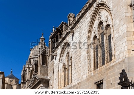 Toledo Cathedral (The Primatial Cathedral of Saint Mary of Toledo) richly decorated Gothic facade with carved windows arches, spires and dome of the Mozarabic chapel.