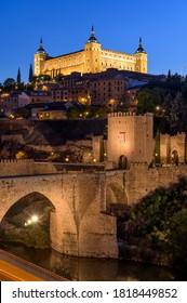 Toledo At Dusk - A Vertical Dusk View Of The Historic City Toledo At Puente De Alcántara - An Ancient Roman Arch Bridge Located In Front Of Eastern City Gate Puerta De Alcántara. 