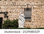 Toledo, Spain – 06-05-2024: Statue of Queen Isabella of Castile in front of the historic Palacio de la Cava, reflecting Spain