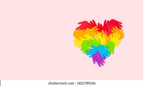 Tolerance, kindness, cooperative, friendship, charity humanitarian aid day concept. Many rainbow color palm hands on pink background with copy space.