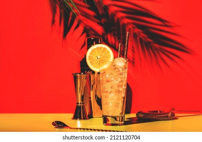 Tom Collins Alcoholic Cocktail With Dry Gin, Syrup, Lemon Juice, Soda, Orange And Ice. Defiant Red Greenbackground, Hard Sun Light