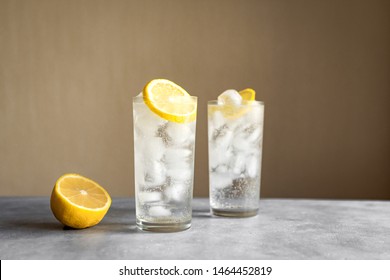 Tom Collins Cocktail or Gin Tonic Cocktail with lemon in classic glasses, copy space.