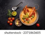 Tom Yam kung Spicy Thai soup with shrimp, seafood, coconut milk and chili pepper in a bowl, top view with copy space