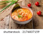 Tom Yam soup with shrimps and ramen noodles on old wooden table