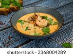 Tom Yum soup. Thai spicy soup with shrimp and coconut milk. Tom Yum kung Spicy Thai soup with shrimp in a grey bowl on a wooden background