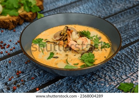 Tom Yum soup. Thai spicy soup with shrimp and coconut milk. Tom Yum kung Spicy Thai soup with shrimp in a grey bowl on a wooden background