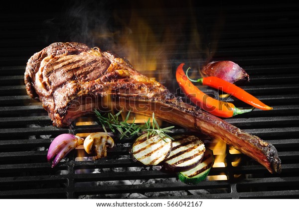 Tomahawk\
rib beef steak on hot black grill with\
flames