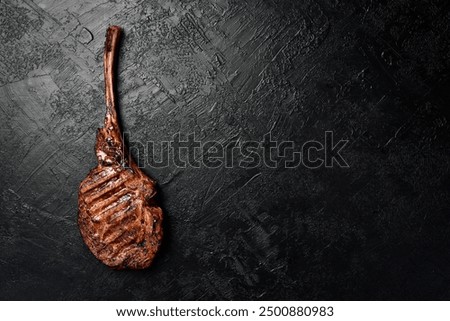 Tomahawk steak on the bone. Prime Black Angus beef steak on a black slate background. Top view.