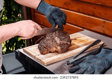 Tomahawk Steak wird auf einem Holzbrett geschnitten und auf eine Servierplatte platziert - Tomahawk Steak is getting cut on a wooden board and placed on a serving plate