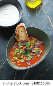 Tomato And Chickpea Soup Served With Fresh Basil Leaves, Ciabatta And Yogurt, Elevated View On A Dark-olive Marble Background, Vertical Shot