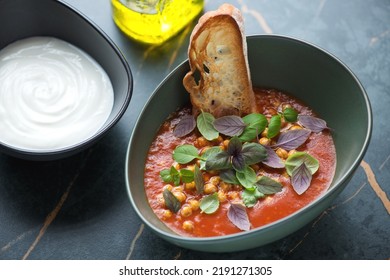 Tomato And Chickpea Soup Served With Fresh Basil, Ciabatta And Yogurt, Horizontal Shot On A Dark-olive Marble Background