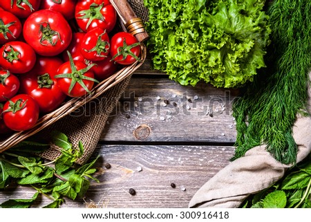 Tomato and green vegetables on the wooden table in the kitchen