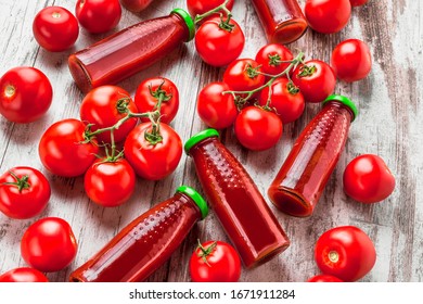 Tomato Juice In Bottles With Fresh Stacked Tomatoes Overhead Vivid Color Arrangement On Bright Light And White Wooden Table In Studio