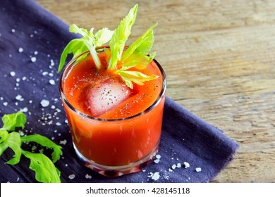 Tomato juice with celery, spices, salt and ice in portion glasses with copy space
