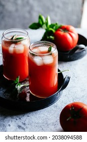 Tomato juice with ice in a glass on a gray background
