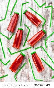 Tomato Juice Overhead Arrangement In Glass Bottles With Green Straws On White Rustic Wooden Table In Studio