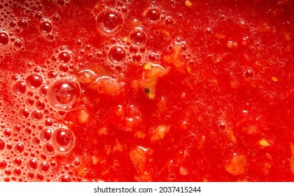 Tomato juice with pulp close-up. On the surface bubbles of different sizes and foam. Fresh natural product for the preparation of sauces, soups and other vegetable dishes.