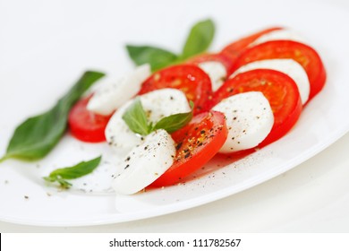 Tomato And Mozzarella With Basil Leaves On A Plate