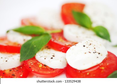 Tomato And Mozzarella With Basil Leaves On A Plate