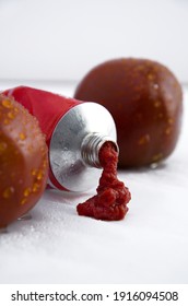 Tomato Paste In A Tube With Wet Purple Black Tomatoes On White Vertical