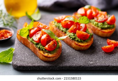 Tomato, Pesto Bruschetta, Crostini With Fresh Basil On Serving Board. Close Up.