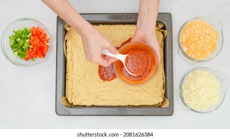 Tomato Pizza Sauce On Pizza Dough. Woman's Hands Spread Sauce, Close Up View From Above