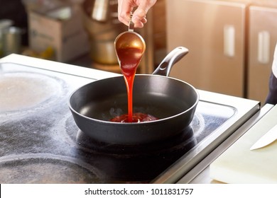 Tomato Red Sauce Flowing Onto Pan. Hand Pouring Sauce From Sauce Boat Onto Pan.