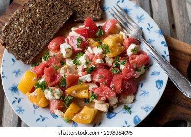 Tomato salad with sheep cheese, olive oil and parley. Served with whole grain bread on a plate - Shutterstock ID 2198364095