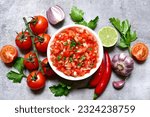 Tomato salsa (salsa roja) - traditional mexican sauce  with ingredients for making on a light grey  slate,stone or concrete background.Top view with copy space.