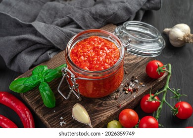 Tomato Sauce In A Glass Jar On The Background Of Ingredients. Italian Marinara Sauce. Side View, Close-up.