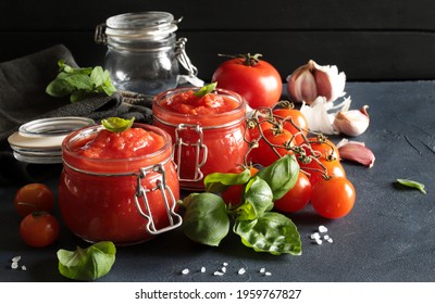 Tomato sauce in glass jars with fresh basil, garlic and tomatoes  on dark background. Close-up. Copy space. - Powered by Shutterstock