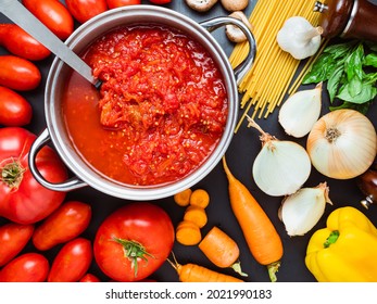 Tomato sauce and pasta in the making: pot with mushed tomatoes and raw vegetabless on the side. - Powered by Shutterstock