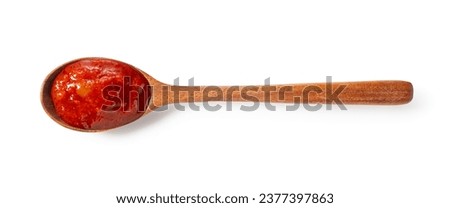 Tomato sauce in a wooden spoon on a white background. View from directly above.