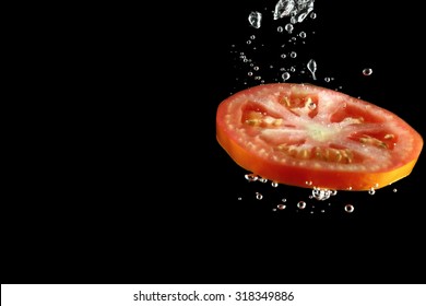 Tomato Slice Falling Into Water At Black Background